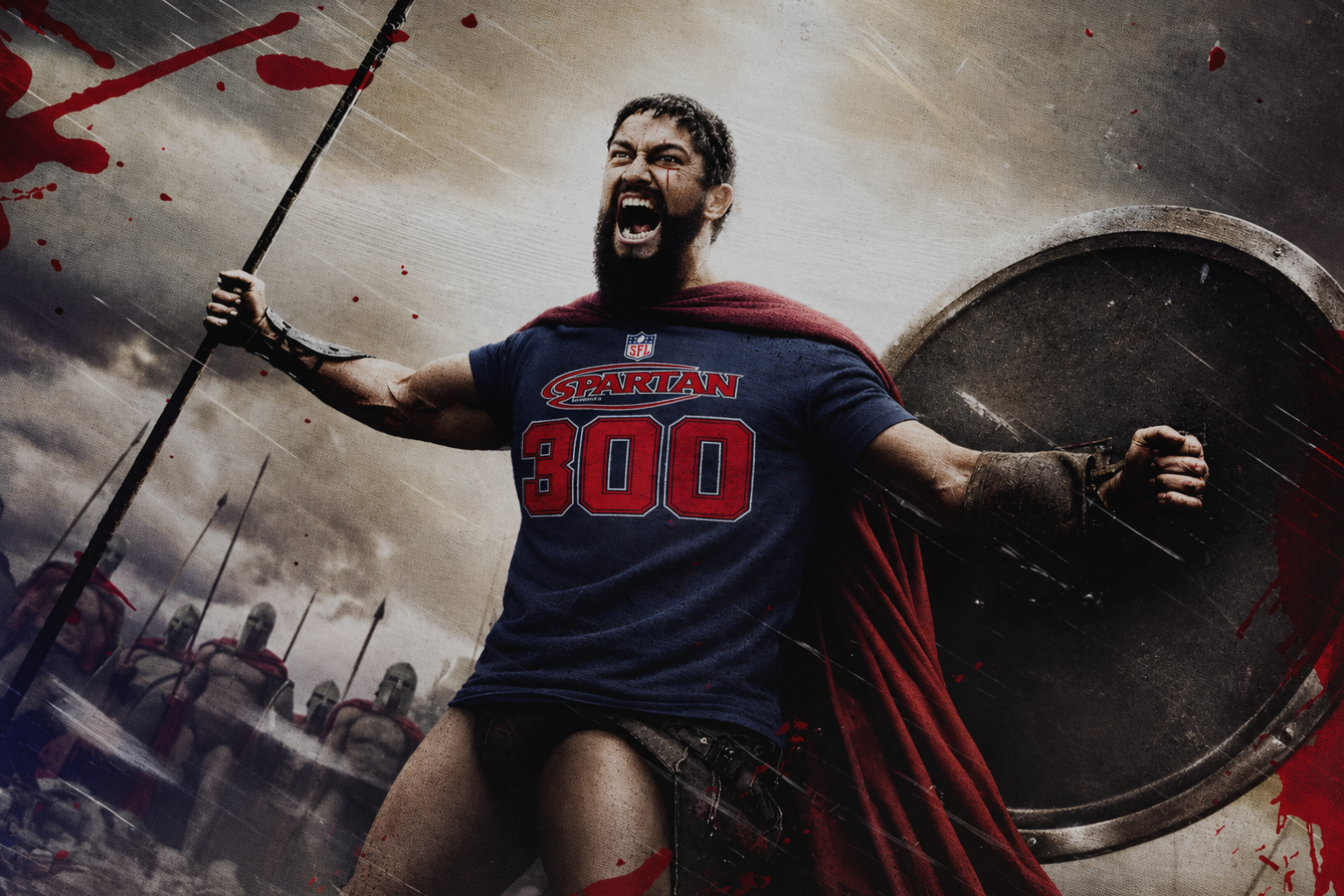 A man in a Spartan-style warrior costume stands dramatically holding a spear and shield, wearing a navy blue T-shirt with 'SPARTAN 300' in red and a red cape, against a smoky battle scene with blood splatters.